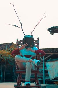 Rear view of man sitting on seat against sky