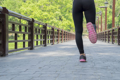 Low section of woman running on footbridge