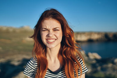 Portrait of smiling young woman against sky