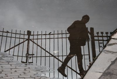 Reflection of man walking in puddle