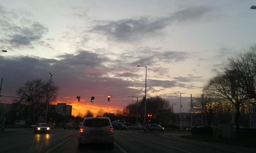 Cars on road against cloudy sky