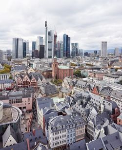 High angle view of city buildings against cloudy sky