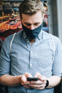 Man wearing mask using mobile phone in train