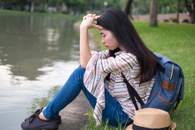 Young woman sitting on grass by water
