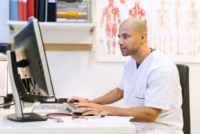 Male orthopedic doctor using computer at desk in clinic