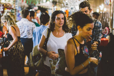 Group of people looking at crowd in city at night