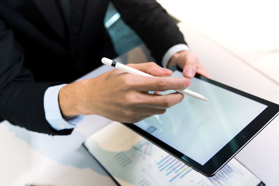 Midsection of businessman using digital tablet at office