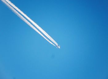 Low angle view of airplane flying against clear blue sky