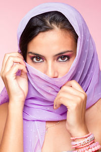 Close-up portrait of young woman covering face with scarf