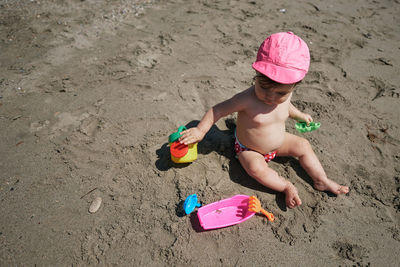 High angle view of girl playing with toy on sand
