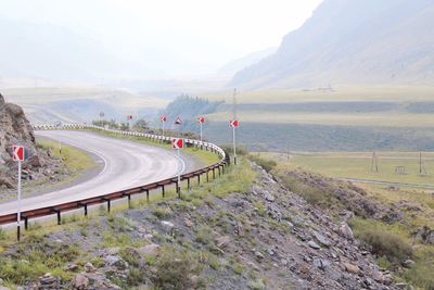 Winding road by field in foggy weather