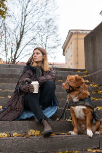 Side view of woman with dog sitting on street