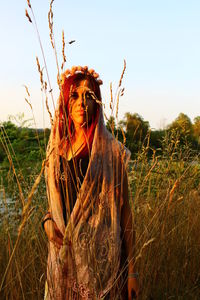 Mid adult woman standing on field against clear sky during sunset