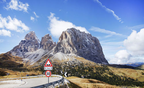 Road by rocky mountains against sky