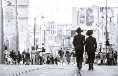 Rear view of people walking on road in city