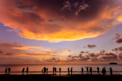 Silhouette people on beach against sky during sunset