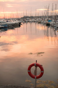 Boat moored at harbor against sky during sunset