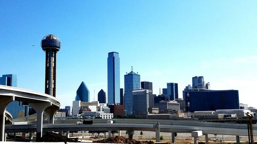 Low angle view of multiple lane highway and buildings in city against clear sky