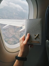Midsection of person holding airplane window