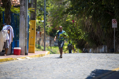 Man walking on footpath by street in city