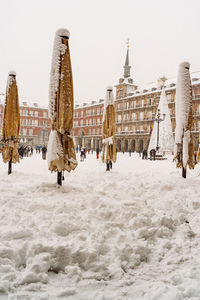 Rear view of people walking on snow covered city against sky