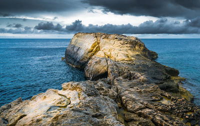 Rock formation on sea shore against sky