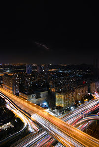 High angle view of illuminated street amidst buildings against sky at night