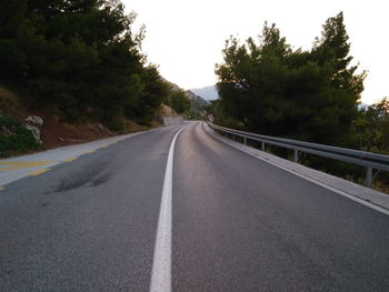 Road amidst trees against clear sky