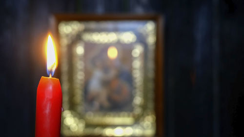 Candle burning in dark against soft focus virgin mary icon. religion and spirituality.