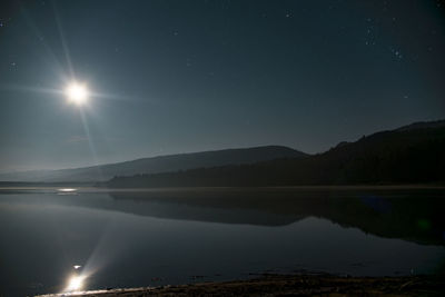 Scenic view of lake and mountains against sky at night