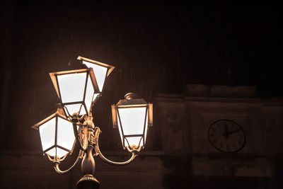 Low angle view of illuminated street light during rainfall at night