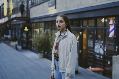 Young woman looking away while standing in city