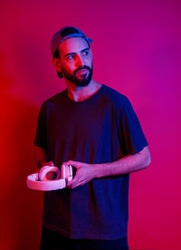 Young man wearing hat standing against red background