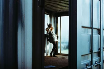 Side view of woman standing by window in building