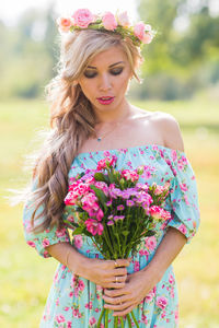 Portrait of beautiful woman standing by pink flower