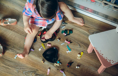 Full length of cute girl playing with toys while sitting on hardwood floor at home