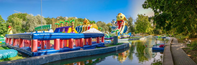 Boats in amusement park by lake against sky