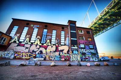 Low angle view of graffiti on wall against blue sky