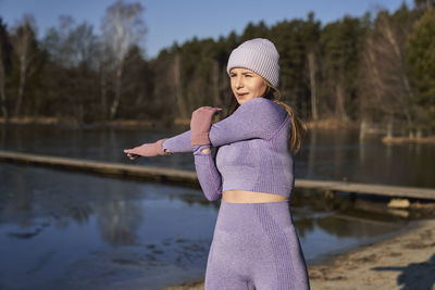 Young woman exercising by lake