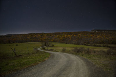 Road amidst field against sky at night