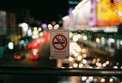 Close-up of no smoking sign in city at night