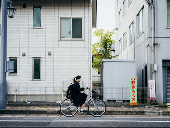 Man riding bicycle on street against building