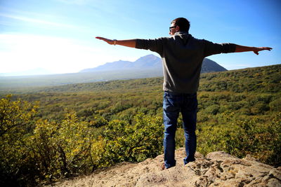 Rear view of man standing on landscape against sky