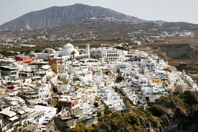 Drone aerial shot of thira village in santorini, oia located in greece against mountains. 