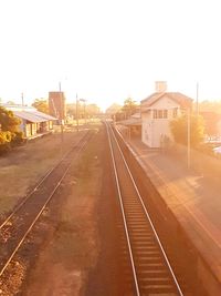 Railroad tracks by buildings against clear sky