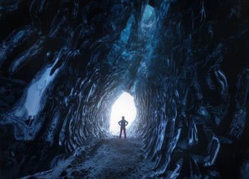 Rear view of woman standing in cave