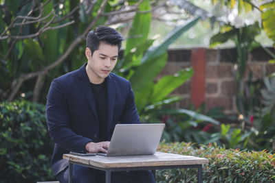 Young man using mobile phone while sitting outdoors