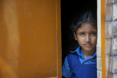 Portrait of girl wearing school uniform standing at entrance