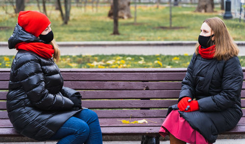 Woman sitting on bench in park during winter