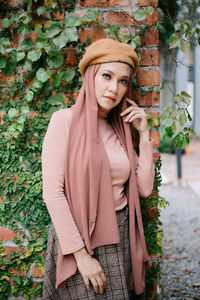 Portrait of beautiful young woman standing against plants